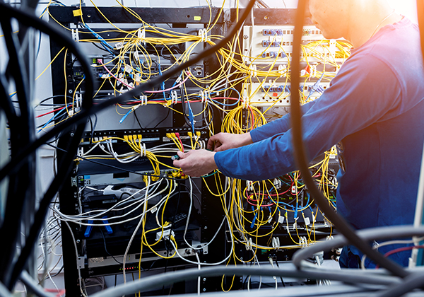 An image of a person working on a network's cabling.