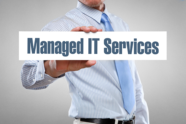 An image of a man holding up a white sign with blue font that says, “managed IT services.”