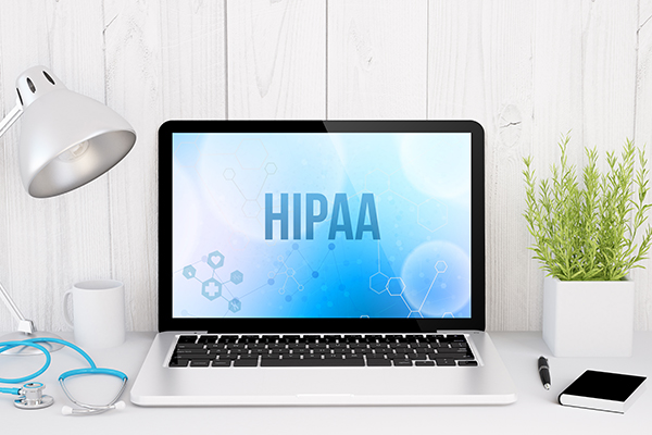 A white laptop with a blue background on it that says “HIPAA.”