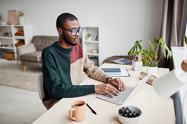 A man sits at his table in front of his laptop, working from home.
